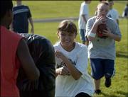 Lynn Robinson, 10, center, puts her shoulder into a pad to provide
a block for Joseph Odrowski, 10, during a handoff and running drill
at the Lawrence and Free State high school youth football camp. The
camp was Tuesday at FSHS.