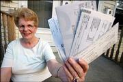 Dale Gravelle holds up some of the credit card statements that she
still owes money on after running up more than $22,500 in debt.
Despite paying her mortgage and car payments on time, Gravelle
managed to run up her credit card debt. Gravelle, pictured July 1
at her home in Attleboro, Mass., is now paying them off using a
debt consolidation company.