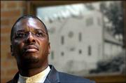 THE REV. REGINALD BACHUS, pastor of First Regular Missionary
Baptist Church, 1646 Vt., will moderate the discussion
"African-American Churches in Early Lawrence: Citadels of Faith,
Hope and Community" at 7 p.m. Wednesday at Lawrence Public Library.
Behind Bachus is a 1951 photo of First Regular Missionary Baptist
Church when it was at 416 Lincoln St.