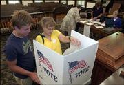 Zach Hertzel, 16, left, watches his mother, Camille Hertzel,
Baldwin, fill out an advance ballot at the Douglas County
Courthouse, 1100 Mass. Hertzel voted Monday for today's primary
election.