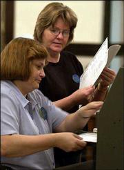 Charlene Conner, left, and Rita Fulks feed ballots into a ballot
counter for the primary election at the Douglas County Courthouse.
Troubles with the machines because of high humidity slowed the
counting process Tuesday.