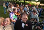 Photographs from above can give a unique perspective. For this
shot, the photographer quickly moved a chair near the bride and
groom, climbed on and aimed the camera from above his head at the
couple and the parading musicians in the background. A sequence of
several shots was fired as the bride hugged a friend and leaned
back laughing.
