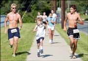 Flanked by Free State High seniors Alex Rock, left, and Danny
Schneider, right, 7-year-old Owen Heffernan sprints to the finish
line at the Crosstown Unity Run. Heffernan, the son of FSHS
cross-country coach Steve Heffernan, was one of 311 runners who
participated in Saturday's event, which followed a course that led
from FSHS to Lawrence High.