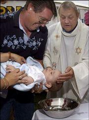 THE REV. JOHN VAKULSKAS BAPTIZES 8-month-old Corbin John Murphy,
held by his father, Bryant Murphy, during a Mass for carnival
workers at the Missouri State Fair in Sedalia, Mo.