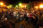 Community members gather in front of the Douglas County Courthouse
for a candlelight vigil to share their stories and songs and to
mourn the loss of life in the war in Iraq. The group gathered
Wednesday night before walking to the Campanile on the Kansas
University campus to join a second vigil in memory of the more than
1,000 U.S. troops killed in Iraq.