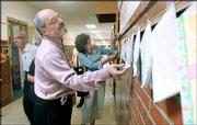 Lawrence Schools Supt. Randy Weseman, foreground, and school board
members Austin Turney, left, and Leni Salkind inspect artwork in
the hallway at Hillcrest School. School board members toured
several school facilities Wednesday in Lawrence.