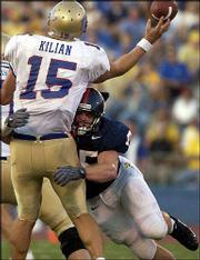 KU's Kevin Kane, right, puts pressure on Tulsa quarterback James
Kilian. Kane had a sack and an interception Saturday in his first
start.