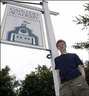 Cape Cod Academy senior M.J. Dean is photographed in front of the
school's sign in Osterville, Mass. The T-shirt and cargo pants he
wears are now no longer allowed under the school's new dress code.