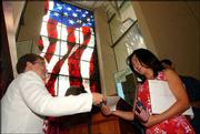 Pamela Williams, left, with U.S. Citizenship and Immigration
Services, hands Kate Young-Choi Kim her certificate of citizenship
at the Dole Institute of Politics.