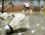 A shuttlecock lies next to the court as six competitors play a game
of badminton at the First Presbyterian Church in Hutchinson.