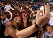 Free State High School seniors Sarah Leslie, left, and Teresa
Wilson snap a photo using a camera phone. They attended the FSHS
Homecoming football game Sept. 17 against Shawnee Mission Northwest
High School at Kansas University's Memorial Stadium.