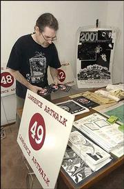 John Wysocki, a Lawrence photographer and organizer of the Lawrence
ArtWalk, sorts through posters and guide books from previous years
of the annual event. Wysocki and other area artists are gearing up
for the 10th anniversary of the self-guided tour of artists'
studios.