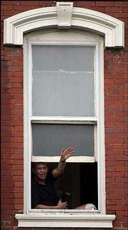 Tom Coen waves to a friend walking in the Sesquicentennial Parade
on Massachusetts Street. Coen and his dog Bandit enjoyed the view
from the second-story window above Hanna's. The parade was Sept.
15.