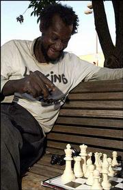 Willie Moore ponders his next move while playing chess at 10th and
Massachusetts streets. The group of chess players has been ordered
by the Lawrence Police to quit playing games on the ground,
limiting the number of games the group can play at once.