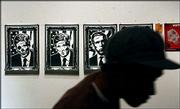 A visitor passes posters hanging on a wall during a political art
exhibition at Track 16 Gallery in Santa Monica, Calif. The
exhibition in this politically liberal beach city drew more than
350 people Friday night.