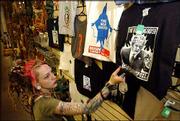 Kristen Ferrell, body jewelry manager at Third Planet, 2 E. Ninth
St., straightens an anti-Bush T-shirt. The store sells anti-Bush
materials on everything from playing cards to posters to T-shirts.
Ferrell arranged the display Thursday.