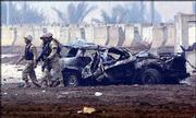 American soldiers pass a vehicle damaged in a car bomb explosion at
a checkpoint at the entrance of the Baghdad International Airport.
Wednesday's bombing killed an American soldier and wounded another.