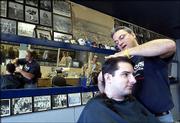 Rex Porter cuts the hair of customer Keiv Spare, a Kansas
University senior from Parsons, at Rex's Stadium Barber Shop, 1033
Mass. Rex bought the longtime RC's Stadium Barber Shop after being
a barber at Downtown Barber Shop for 17 years. Porter said Friday
that he originally wanted to remodel the wall featuring pictures of
local athletes, but since had decided leave it alone.
