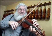Steve Mason, a multi-instrumentalist, member of the Alferd Packer
Memorial String Band and long-time supporter of musical arts in
Lawrence, is the recipient of this year's Phoenix Award for Music
Arts. In keeping with his zany sense of humor, Mason has a friend
lend him a third hand while fiddling a tune.