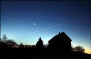 In a rare alignment, the crescent moon and the planets Venus,
center, and Jupiter shine above a farmhouse in the eastern pre-dawn
sky in Brunswick, Maine. The contrail of a southbound jet bisected
the scene early Wednesday. Today and Friday, the two planets will
appear at their closest, less than 1 degree apart, although they
are in fact separated by about 462 million miles.
