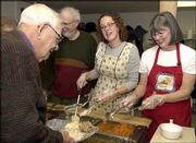 Richard Gwin/Journal-World File Photo Arvid Grover, left, receives
his meal from Aime Pennel and Kathy Davis at the Lawrence
Interdenominational Nutrition Kitchen&squot;s annual free Thanksgiving
dinner. Grover sang a round of "God Bless America" to the
volunteers before going through the serving line last year at First
Christian Church, 221 W. 10th St.