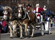Santa Claus parades down Massachusetts Street in a horse-drawn
carriage under the reins of Rob Phillips, who helped organize the
Old-Fashioned Christmas Parade. Thousands lined Lawrence's downtown
for a look at the 11th annual yuletide celebration.