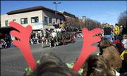 Framed by a set of decorative reindeer antlers, a box wagon steered
by Lester and Betty Edmunds crosses the intersection of Ninth and
Massachusetts streets during the annual Old-Fashioned Christmas
Parade.