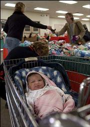 One-month-old Ayla Clark rests in a shopping cart as her mother,
Sarah Acock, upper left, shops for gifts at the Toy Shop at the
Douglas County Fairgrounds. The Toy Shop distributed gifts and
clothing to families Monday at the fairgrounds. The annual event is
co-sponsored by the Salvation Army and Toys for Tots.
