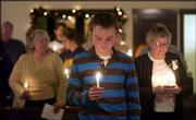 Dustin Land, 20, above, holds a candle during a moment of silence
at Wednesday's service. Land, whose father is the church's pastor,
is from Lee's Summit, Mo.<br>