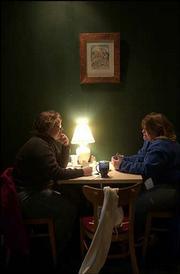 Jennifer Greever, left, and Michelle Cray, enjoy some hot chocolate
and conversation at Aimee's Coffee House, 1025 Mass. One of
Lawrence artist LeRoy Seay's art pieces hangs above their table.