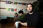 Lawrence artist Brett Allen, foreground, enjoys a cup of coffee at
La Prima Tazza, where his artwork is on view. Patrons Rhiana Huff,
left, and Andre Huffman are pictured in the background.
