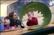 Marea Atchinson, 2, from left, Alee Phillips and her son, Ike, seen
through his birthday crown hat, celebrate Ike's second birthday in
his classroom at Hilltop Child Development Center on the Kansas
University campus. Phillips, a lecturer in the business department
at KU, was present for the party on Tuesday. KU uses the center to
provide child care for its students, faculty and staff. Sen. Pat
Roberts, R-Kan., has introduced a bill in Congress that would
provide federal grants for child care to small businesses.