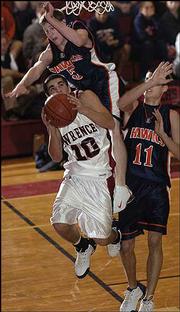 Lawrence High senior Brennan Bechard is fouled by Olathe East's
Blake Bales (5), as Derek Miller (11) trails the play, in the first
half. Bechard was 9-for-9 from the free-throw line, scoring 15
points in the Lions' 70-65 come-from-behind victory Friday night at
LHS.