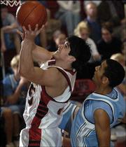 Lawrence High's Ian Handshy, left, shoots over Shawnee Mission East
defender Garrett Webb. The Lancers beat the Lions, 75-60, Friday at
LHS.