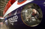 Viewed through one of the plane's portholes, flight engineer Philip
Grassa works in the cockpit of the GlobalFlyer in a hanger at the
Salina Municipal Airport in Salina Monday.