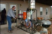 Andy Booth, vice president of the Lawrence Brewers Guild, cleans
his homemade brewery, made of kettles, hoses and propane burners.
