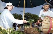 Jane Live, of Lawrence, buys garlic from Mark Lumpe of Wakarusa
Valley Farm last summer at the Lawrence Farmers Market. A workshop
Saturday at the Douglas County Fairgrounds will introduce new
vendors to the market and help veteran vendors polish their
presentations.