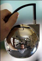 Reflected in a Hemming brand tea pot, Carl Masters displays one of
the many high-design products carried at KOJO, Eighth and New
Hampshire streets. Masters, a Kansas University graduate, sells
local and imported furniture, kitchenware and everyday items at the
shop, which opened in December.