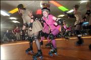 A Bionics jammer, center, designated by a star worn on her helmet,
tries to sneak through a pack of Dogfightin' Dames blockers to
score points. The Dogfightin' Dames took on The Bionics on March 19
at the Winnwood Skate Center in Kansas City, Mo.