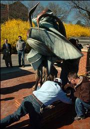 Jeff Weinberg, left, assistant to the chancellor, and artist Jon
Havener, middle, watch as workers place the sculpture "Korean
Cranes Rising" Friday morning on Memorial Drive, completing the new
Korean War Memorial at KU.
