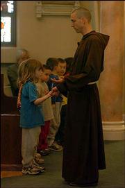 Pastor John Schmeidler holds the hand of Simon Elwell, 9, during a
special Mass Friday afternoon at St. John the Evangelist Catholic
Church, 1229 Vt. The Mass was in honor of Pope John Paul II.