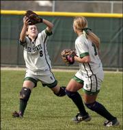 Free State High outfielder Aleese Kopf, left, catches a pop fly in
front of teammate Jamie Stanclift. The Firebirds beat Olathe South,
3-0 and 4-1, Friday at Free State.
