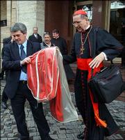 U.S. Cardinal Roger Mahony, of Los Angeles, hands over his robe to
his driver as he leaves the North American College in Rome on his
way to the Vatican. Cardinals had a few last hours Sunday to confer
with aides or pray with faithful before they were required to
check-in at the Domus Sanctae Martae at the Vatican, where they
will be sequestered during the conclave to elect the next pope.