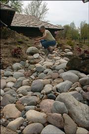 Kansas Insurance Commissioner Sandy Praeger tinkers with stones in
her recently installed dry creek bed. The faux stream adds beauty
to Praeger's yard but also solves a drainage problem.