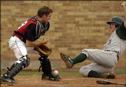 Lawrence High catcher Brett Sims, left, drops the ball, allowing
Free State High's Cory Cooper to score.