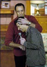 Ray Romano, holding the microphone, star of "Everybody Loves
Raymond," introduces co-star Brad Garrett to the studio audience
before a taping of one of the final episodes of the show at Warner
Bros. Studios in Burbank, Calif. The final episode aired Monday
night.