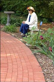 Gladys Staab sits on a bench smelling the aroma at the Audio-Reader
sensory garden, 1120 W. 11th St., at Kansas University.