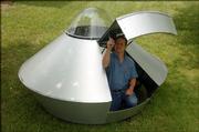 Pat slimmer flips the hatch to a flying saucer he created for Lawrence's 10th annual Art Tougeau Parade. A tongue-in-cheek rendering of George W. Bush being launched to Mars, shown in upper righ-hand corner, is on the saucer door.