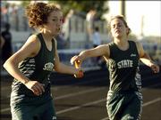 Free State High's Kaitlin Squier, left, takes the baton from Robyn Lee during the girls 3,200 relay at a Class 6A regional. FSHS was second in the event Friday at Olathe District Activities Center.