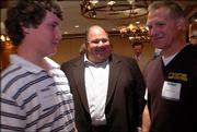 Kansas University football coach Mark Mangino, center, visits with Derec Olson, left, and his father Todd Olson after a Lawrence Chamber of Commerce breakfast. Mangino spoke Tuesday at the Hereford House about the 2005 season and fielded questions from the audience.